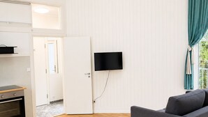 A modern living space with a kitchen, a flat-screen TV mounted on the wall, and a grey sofa. - Bokloster Longstay (Stockholms län)