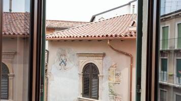 Un edificio con tejado de baldosas, una ventana con contraventanas y un mural en la pared.