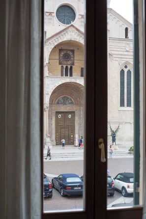 A view through a window of a building with a large clock, arched doorways, and a statue. - Residenza Duomo3 Apartments (Verona)