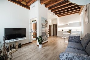 A modern living room with a flat-screen TV, a sofa, and a dining area with a table and chairs. - Residenza Duomo3 Apartments (Verona)