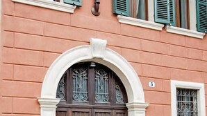A building with a double wooden door, green shutters, and a small window with a metal grill. - Residenza Duomo3 Apartments (Verona)