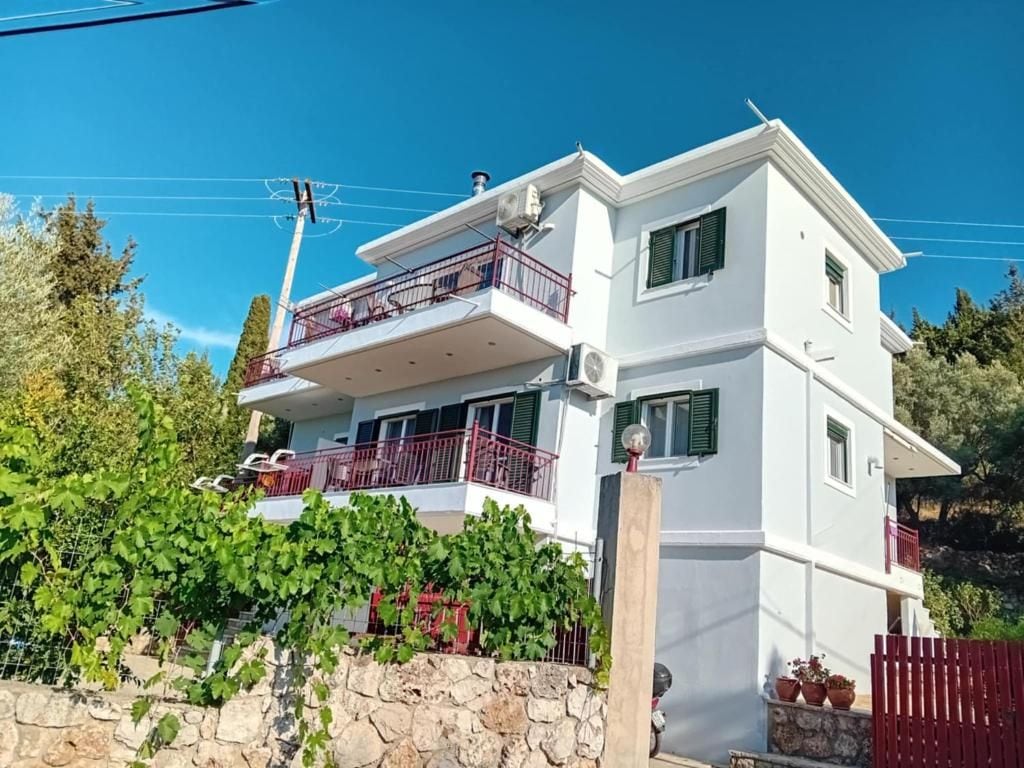 A two-story building with a balcony, a stone wall, and a red fence.