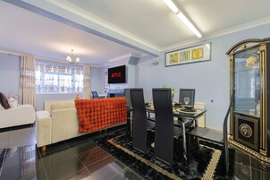 Una sala de estar moderna con sofá, mesa de centro, televisor y un comedor con sillas y mesa.