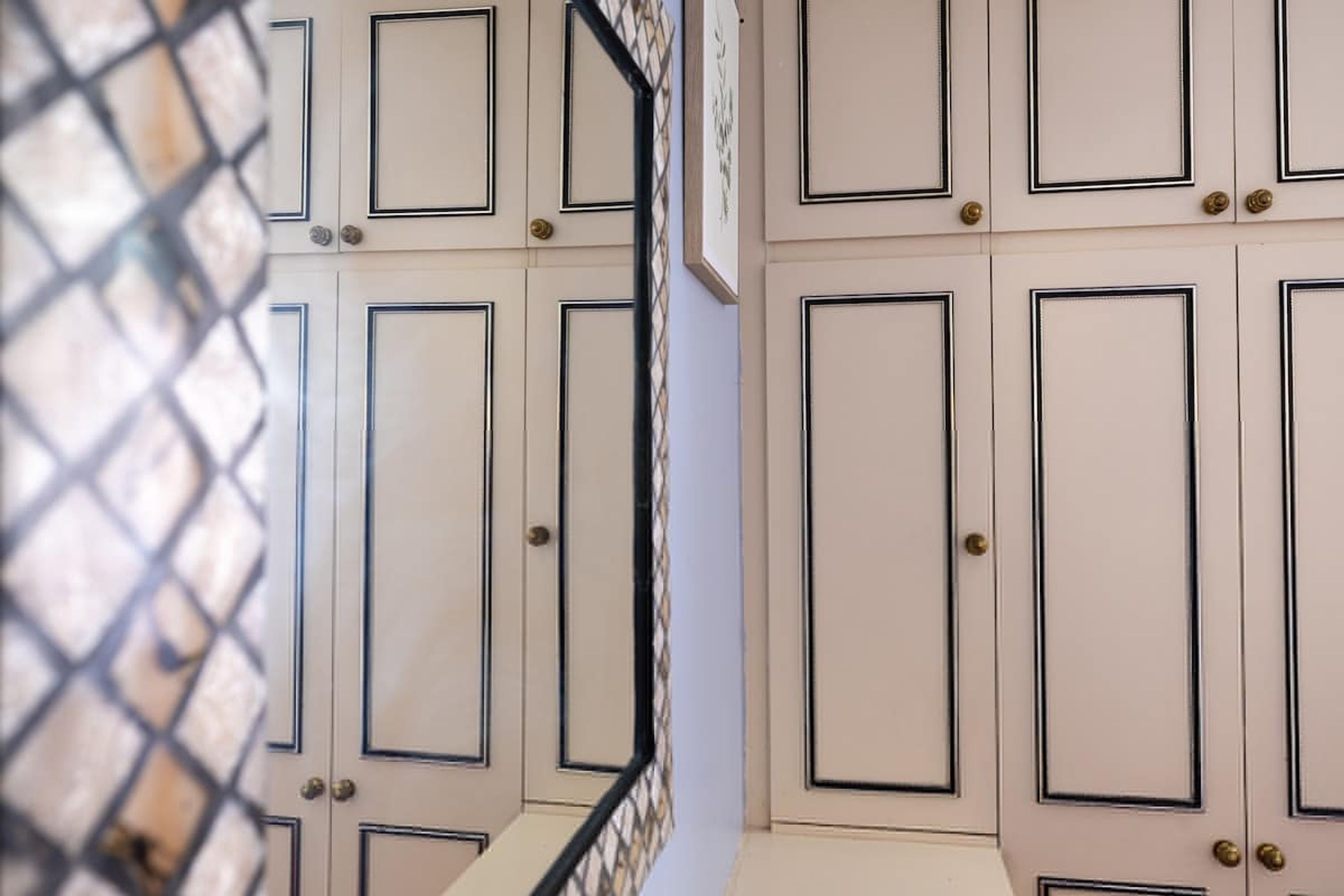 A series of closed doors with a consistent design, featuring a central panel and a smaller panel at the top, with a metal handle on each door.