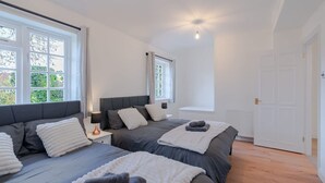 Ein Schlafzimmer mit zwei Betten, einem Nachttisch, einem Fenster und einer Tür.