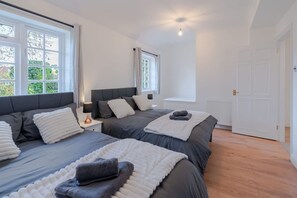A bedroom with two beds, a nightstand, a window, and a door. - 3BR House w Parking Family-friendly Sleeps 8 (London)