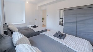 Ein Hotelzimmer mit zwei Betten, einem großen Spiegel und Blick auf den Flur.