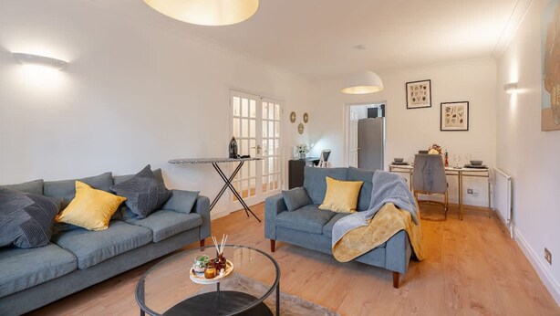 Ein modernes Wohnzimmer mit zwei grauen Sofas, einem Couchtisch und einem Essbereich mit Tisch und Stühlen.