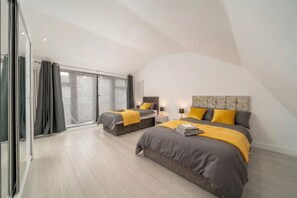 A modern bedroom with two beds, a large window, and a sliding door. - Comfy 3BR House Near Tottenham Stadium Parking (London)