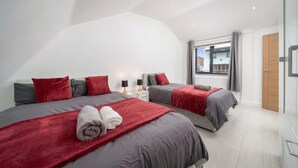 A modern bedroom with two beds, a large window, and a view of the outside. - Comfy 3BR House Near Tottenham Stadium Parking (London)