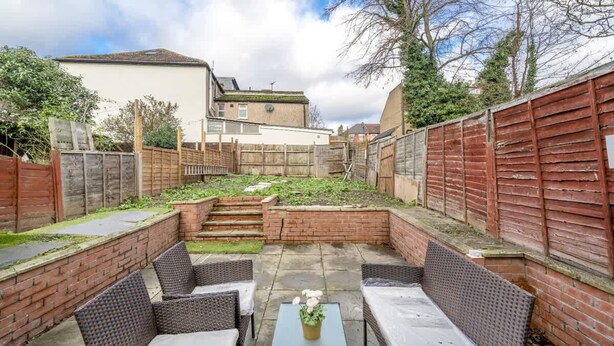 A patio area with wicker furniture, a small table, and a brick wall. - Specious 2BR Family Home Parking Sleeps 6 (London)