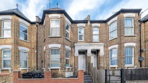 A row of terraced houses with brick facades, white window frames, and a central entrance with a door. - Specious 2BR Family Home Parking Sleeps 6 (London)