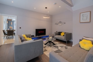 Ein modernes Wohnzimmer mit grauem Sofa, Couchtisch und Flachbildfernseher.