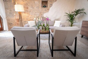 A room with a stone wall, a sofa, two armchairs, a coffee table, and a lamp. - Villa Hedera - beautiful stone house on Hvar (Dol)