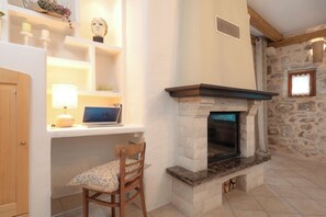 A room with a stone fireplace, a wooden chair, a desk with a laptop, and a shelf with decorative items. - Villa Hedera - beautiful stone house on Hvar (Dol)