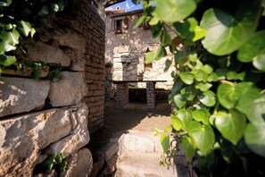 An outdoor stone structure with a bench and potted plants, surrounded by greenery. - Villa Hedera - beautiful stone house on Hvar (Dol)