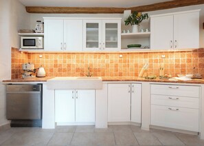 A kitchen with white cabinets, a microwave, a coffee machine, and a sink. - Villa Hedera - beautiful stone house on Hvar (Dol)