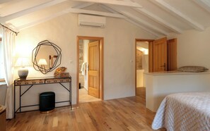 A bedroom with a bed, a bedside table, a lamp, a mirror, and a door leading to another room. - Villa Hedera - beautiful stone house on Hvar (Dol)