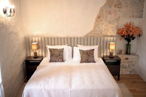 Ein Schlafzimmer mit einem Bett, zwei Nachttischen, einer Wandlampe und einer Steinsäule.