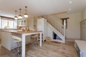 A modern kitchen with a central island, white cabinetry, and pendant lighting. - K Suites - Cozy Rural 1 bed Cottage w/ Garden views (Cheltenham)