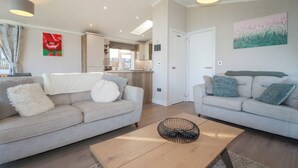 A modern living room with two sofas, a coffee table, and a kitchen in the background.