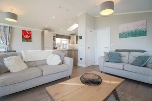 A modern living room with two sofas, a coffee table, and a kitchen in the background.
