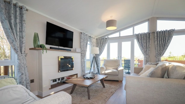 A modern living room with a flat-screen TV, a fireplace, a sofa, and a dining table.