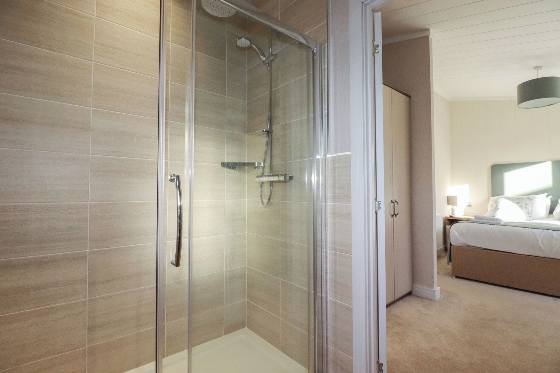 Un baño moderno con cabina de ducha de vidrio, un perchero y un cabezal de ducha.