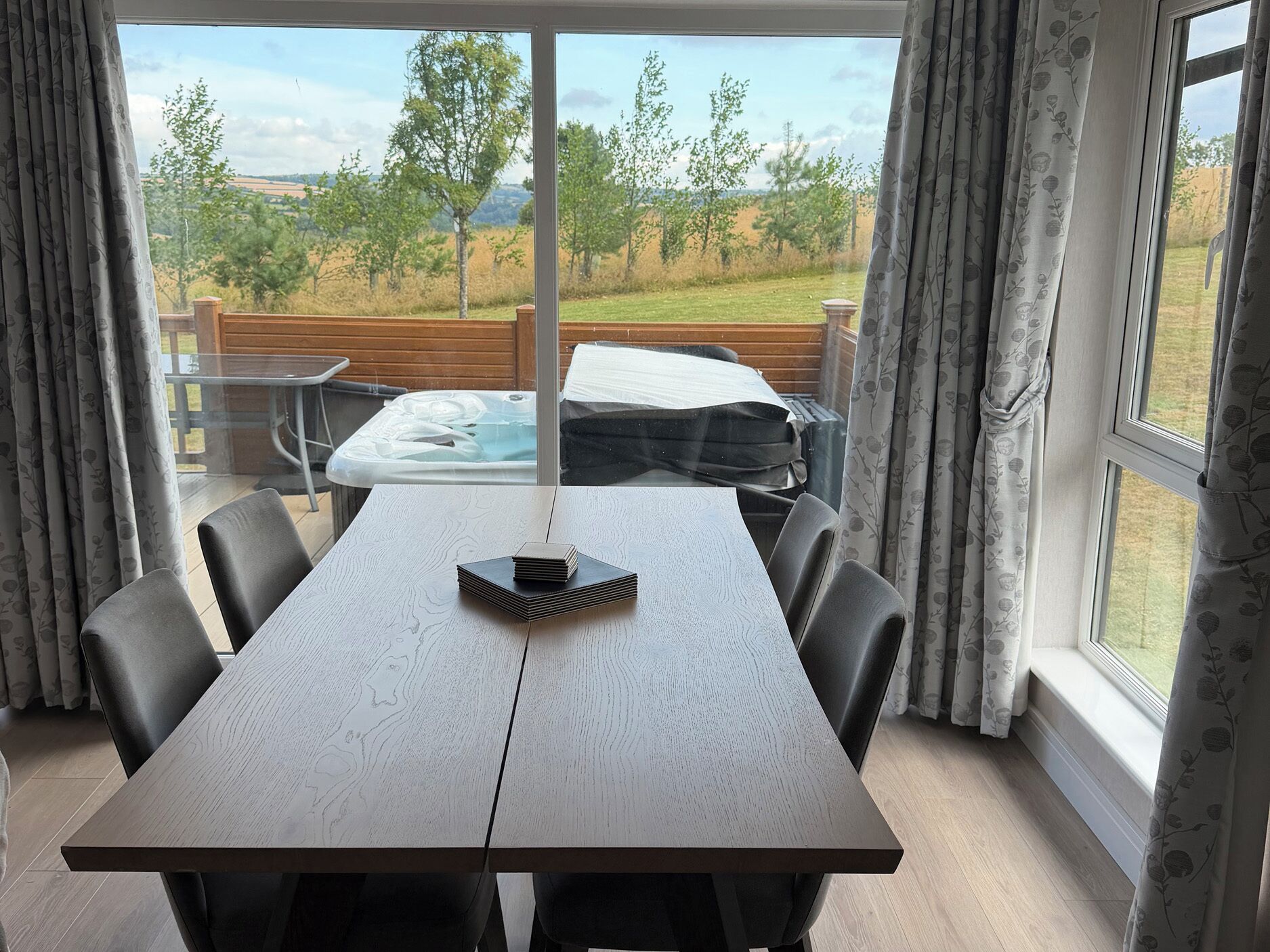 Un comedor con mesa y sillas, una bañera de hidromasaje y vistas al exterior.