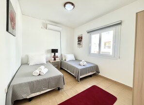 Ein Hotelzimmer mit zwei Betten, einem roten Teppich, einem Fenster und einer Klimaanlage.