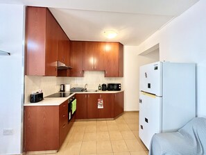 Eine kleine Küche mit Holzausstattung, einem eingebauten Ofen, einer Mikrowelle und einem weißen Kühlschrank.