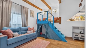 A room with a blue sofa, a staircase, and a kitchen area. - Casa de Limon (La Vega)