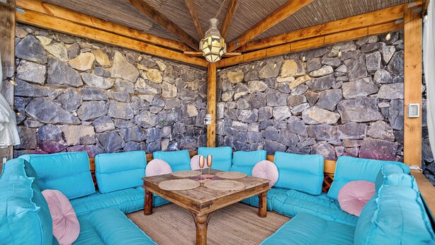 A stone-walled room with a wooden ceiling and a blue sofa set. - Casa de Limon (La Vega)