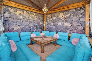 Una habitación con paredes de piedra, techo de madera y un conjunto de sofá azul.