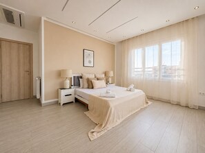 Un dormitorio de hotel con cama, mesitas de noche, una ventana y una puerta.