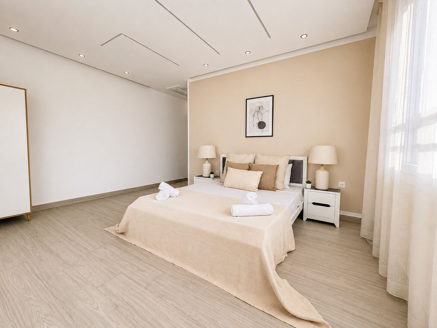 Una habitación de hotel moderna con una cama, mesitas de noche y un amplio ventanal con cortinas.
