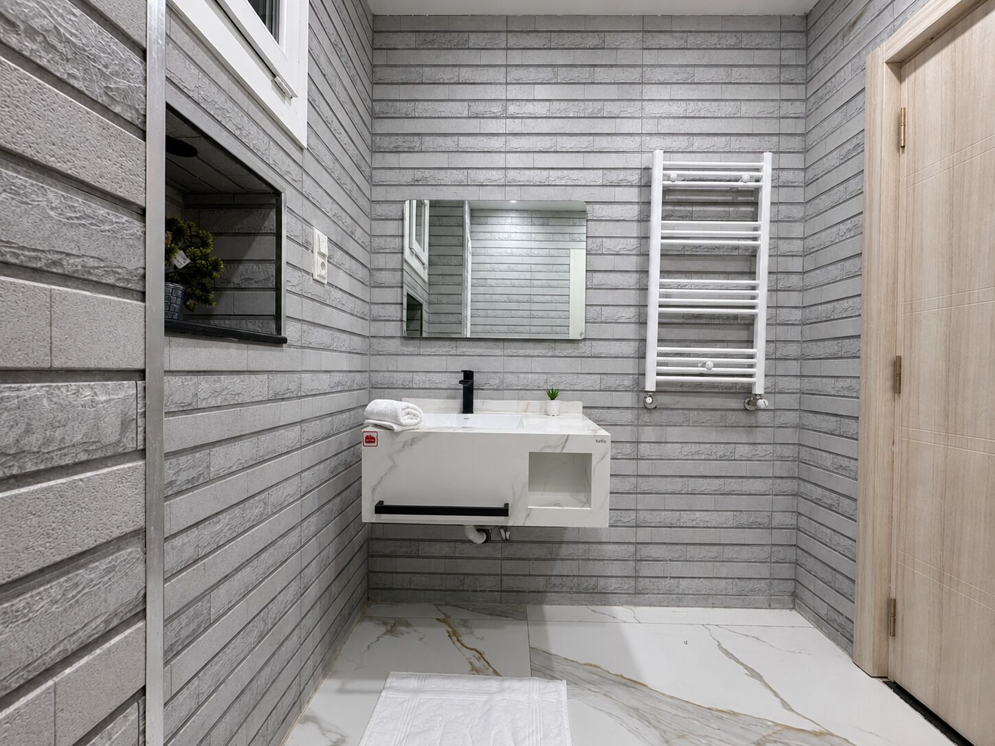 Een badkamer met een witte wastafel, een spiegel en een handdoekhouder.