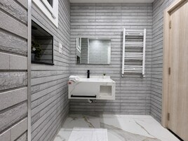 Un baño con lavamanos blanco, un espejo y un perchero para toallas.