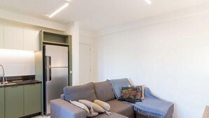 Ein kompakter Wohnbereich mit einer Küchenzeile, einem Sofa und einer Tür zu einem weiteren Raum.
