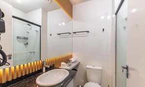 Ein modernes Badezimmer mit einer Glasdusche, einem weißen Waschbecken und einer Toilette.