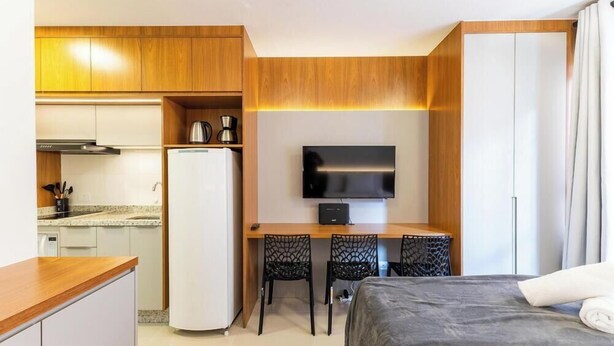 A compact hotel room with a kitchenette, a bed, a desk with two chairs, a television, and a wardrobe. - Studio in a Cond. With a gym in Downtown Muv0811 (Curitiba)