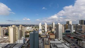 A cityscape with multiple high-rise buildings, a clear sky, and a distant view of the city. - Studio in a Cond. With a gym in Downtown Muv0811 (Curitiba)
