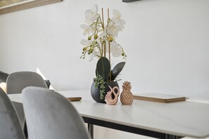 Taula de menjador amb una orquídia en test, un cigne decoratiu i un enfeina de pinya.