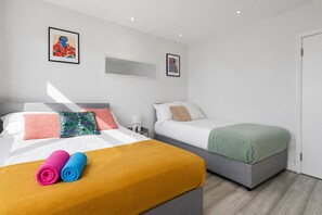 Habitació d'hotel amb dos llits, una tauleta de nit i obra d'art a les parets.
