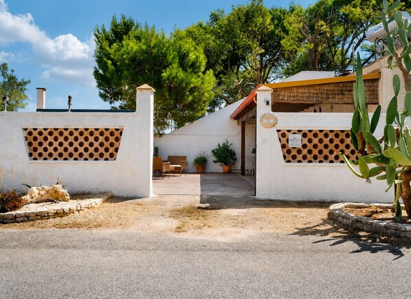 A gated entrance with a covered patio area, a small seating arrangement, and potted plants.