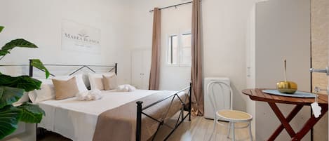 Un dormitorio con cama, escritorio, silla, planta en maceta y aire acondicionado de pared.