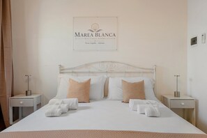 Habitación de hotel con una cama, dos mesitas de noche y un cartel sobre la cama.