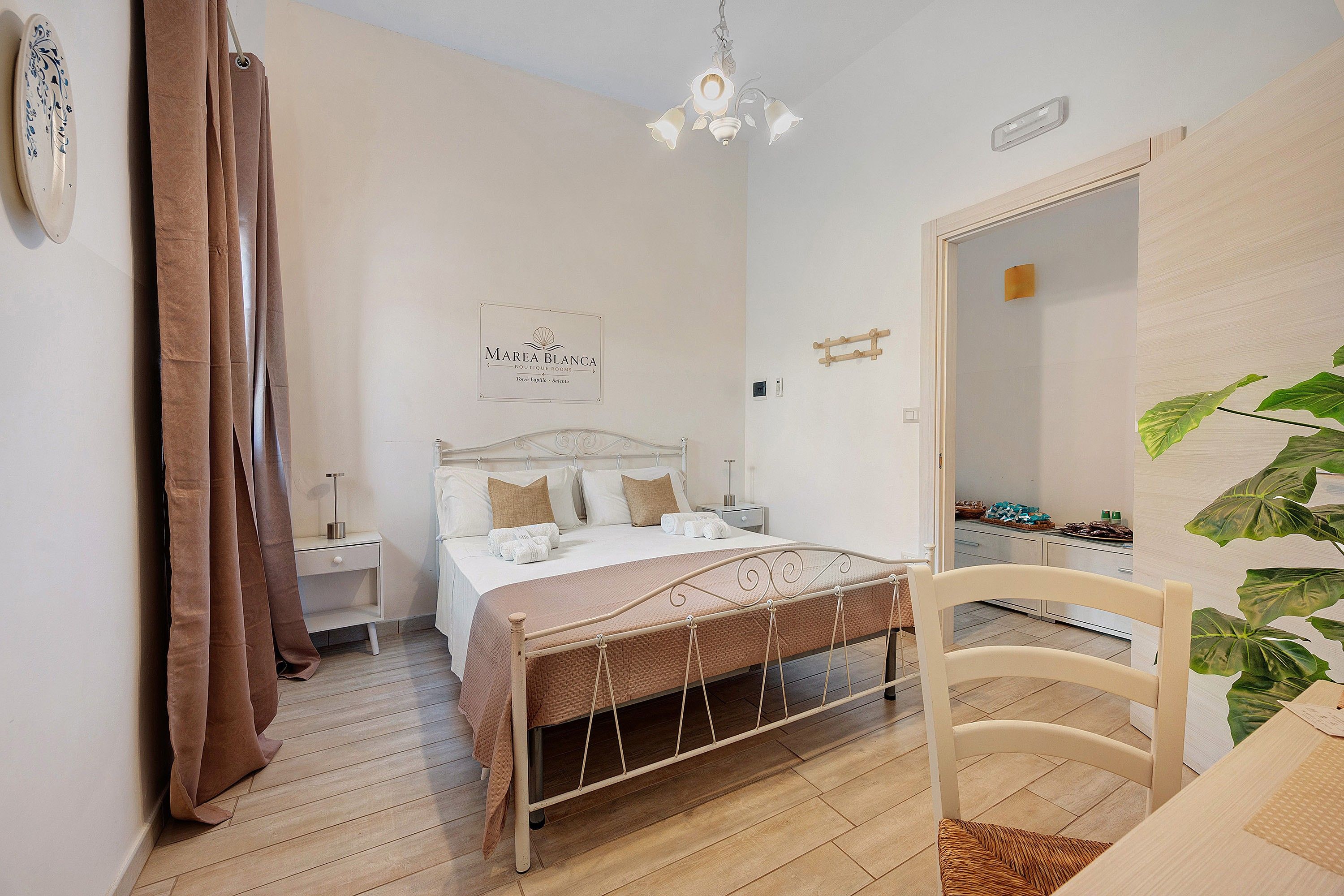 A bedroom with a bed, bedside table, nightstand, and a mirror.