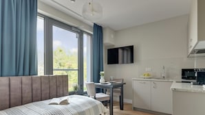 A modern bedroom with a bed, a dining area, and a kitchen.