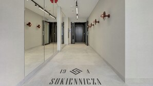 A hallway with mirrored walls, a tiled floor, and a door at the end.